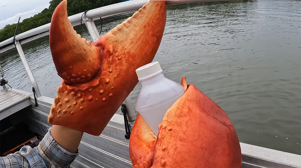 A water sample being taken with red claw gloves on.