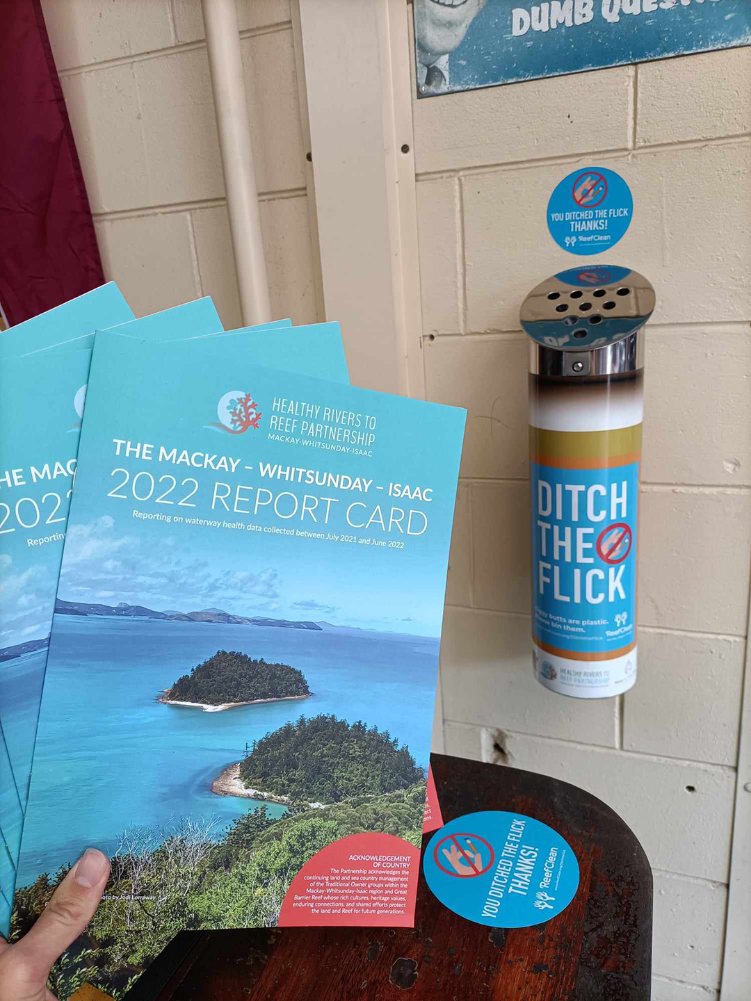 Copies of the 2022 Report Card next to a cigarette butt bin.