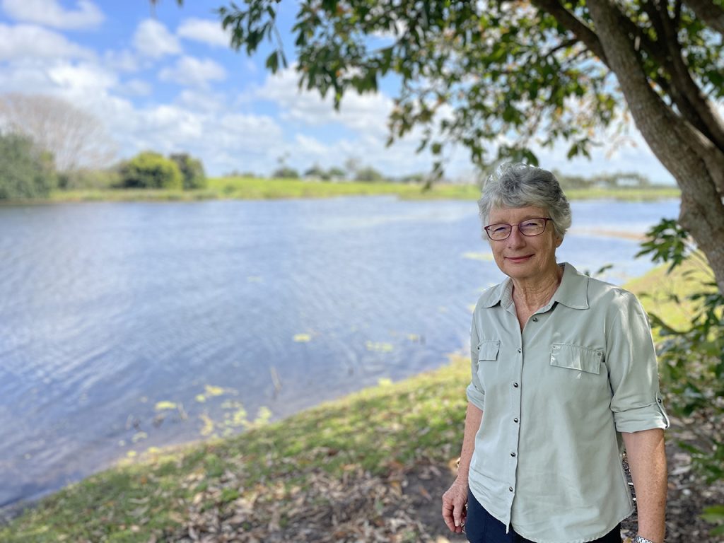 A woman standing in front of a lagoon.