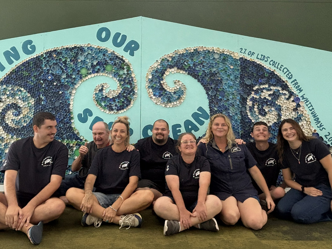 The Eco Barge team with the mural created from recycled marine plastics displayed at Whitsunday Coast Airport.